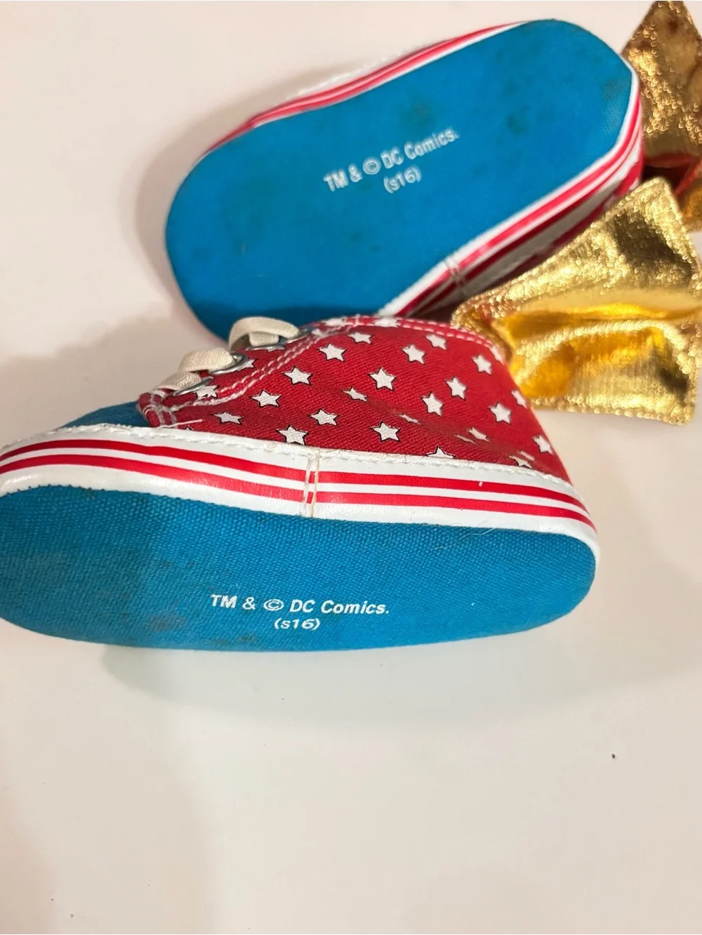DC Comics baby sneaker with Wonder Woman logo. Red canvas with Gold Capes.